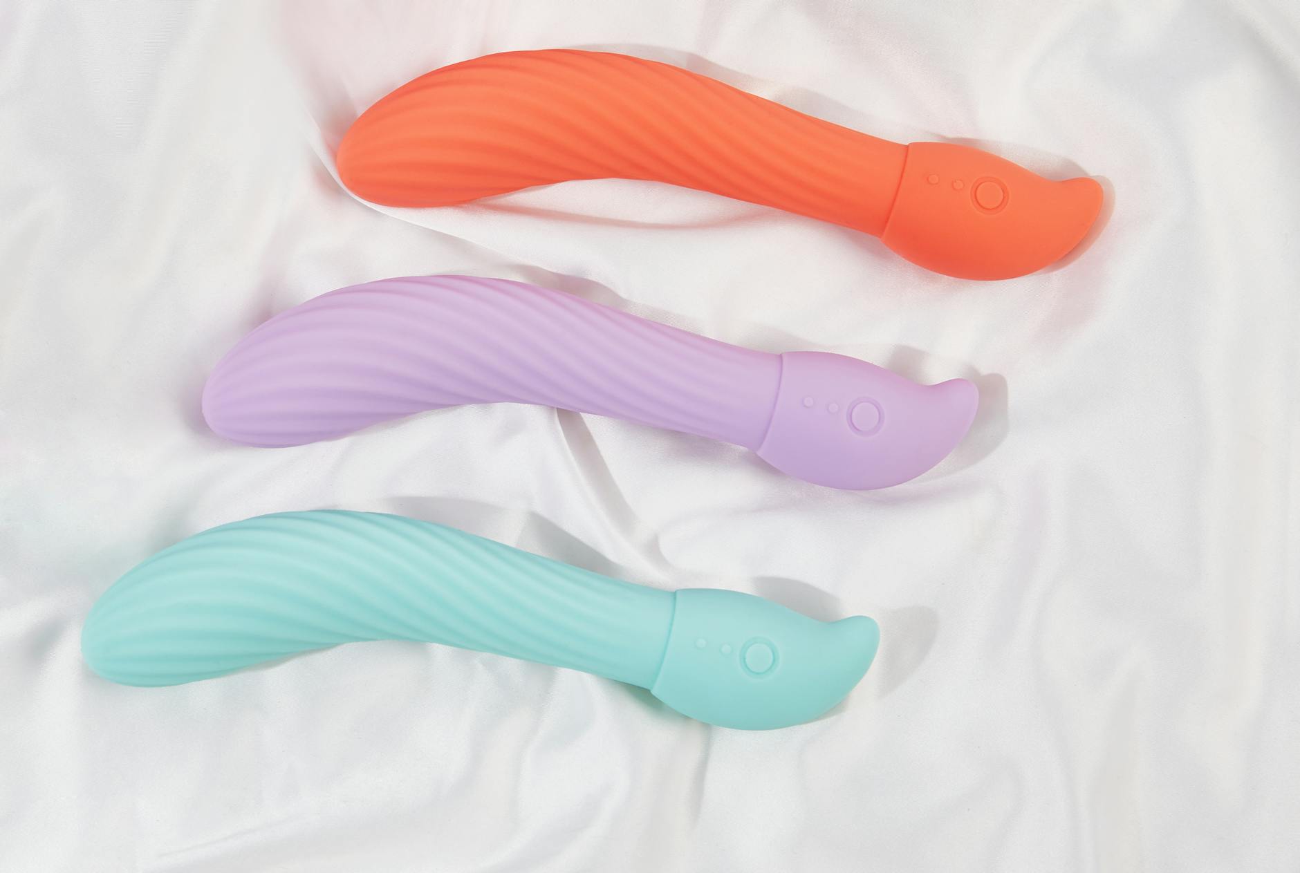 A blue silicone clitoral vibrator held in hand against a solid purple background, symbolizing sexual wellness and self-discovery in partnerships.