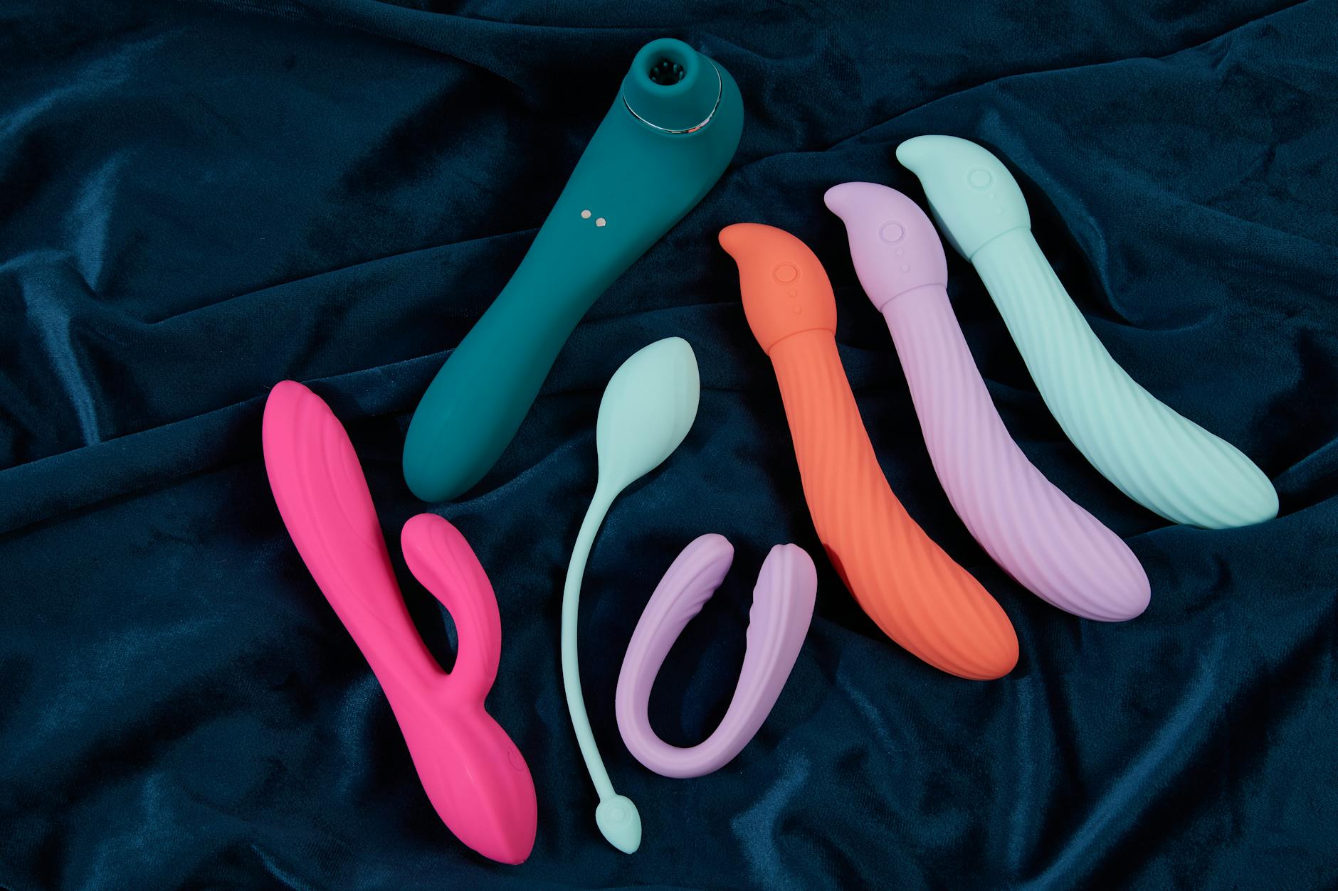 Woman holding blue and pink silicone vibrators in a thoughtful moment, considering her return to pleasure