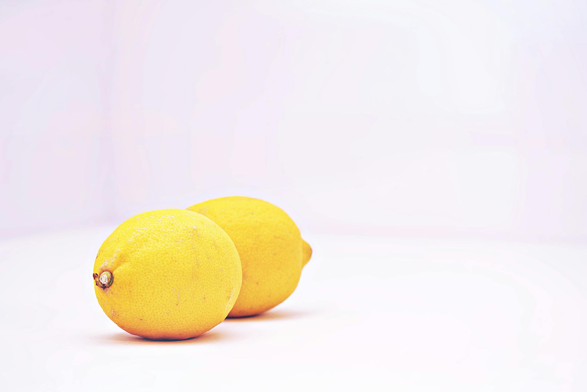 Two vibrant lemons against a minimalistic white background, representing clarity and freshness in pleasure exploration