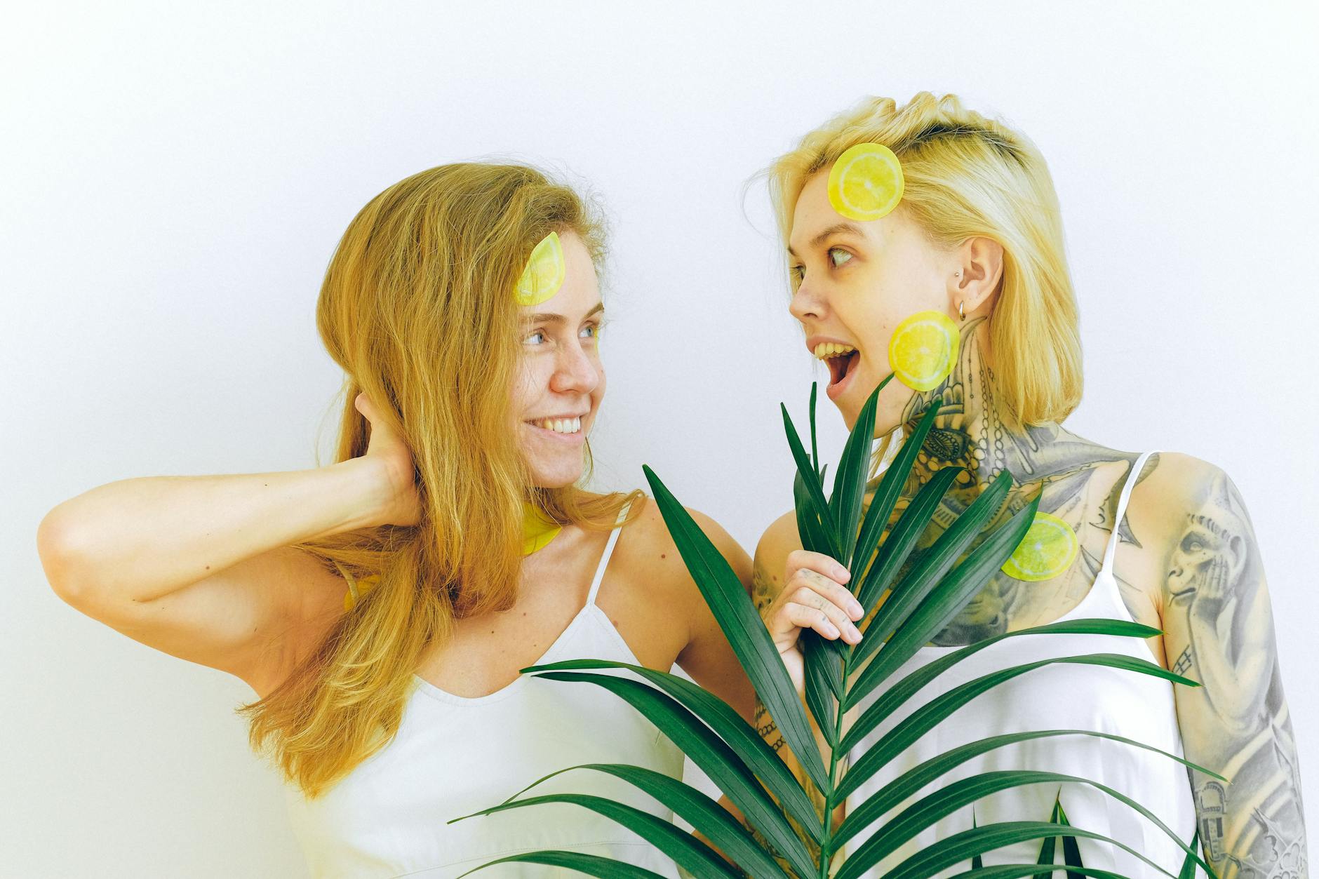 Two women smiling and laughing together with lemon slices, expressing joy and friendship.