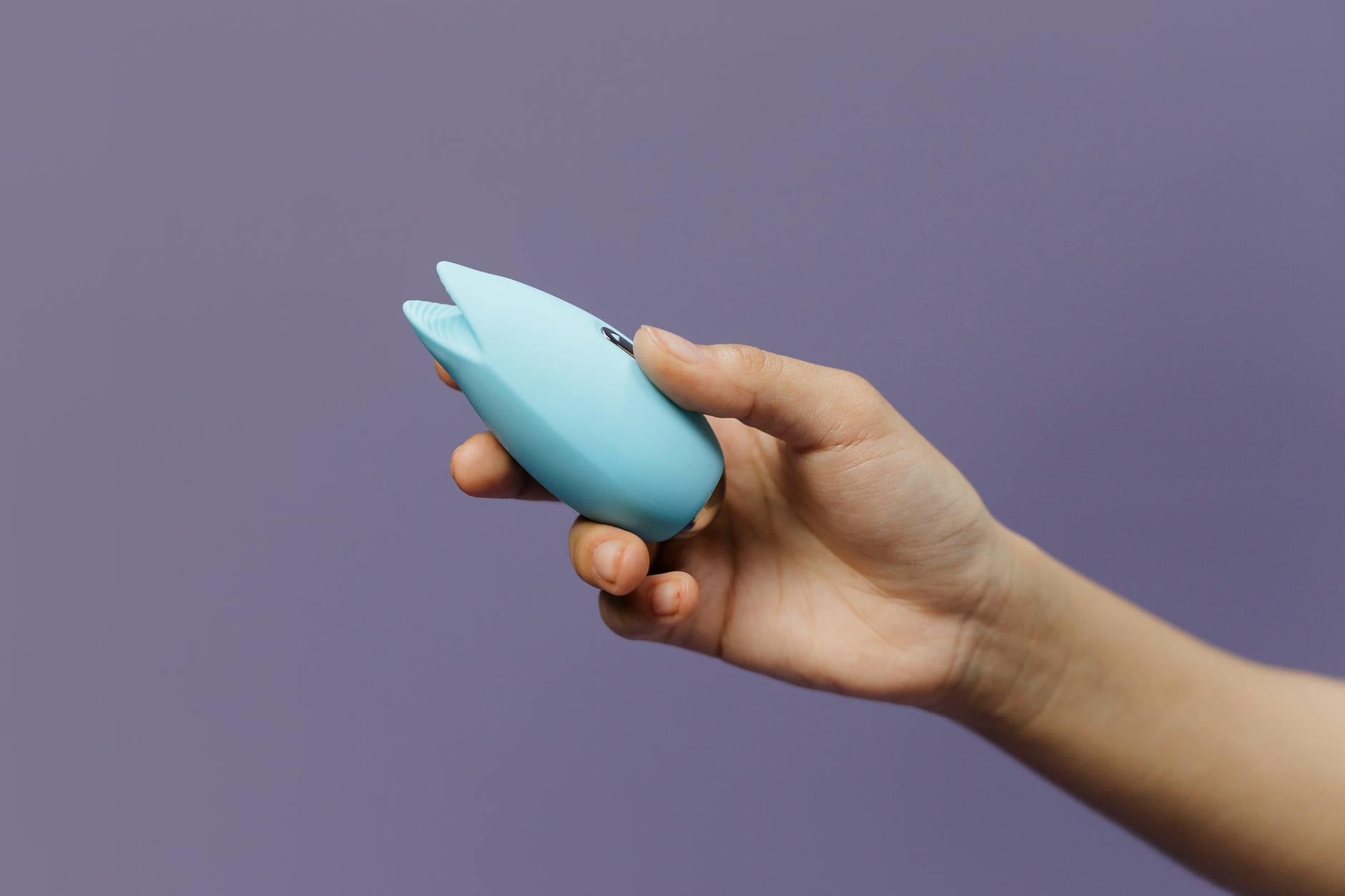 A blue silicone clitoral vibrator held in hand, symbolizing modern approaches to rebuilding intimate connection